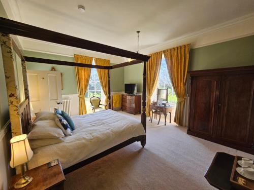 sypialnia z dużym łóżkiem z baldachimem i biurkiem w obiekcie Sloley Hall w mieście Tunstead