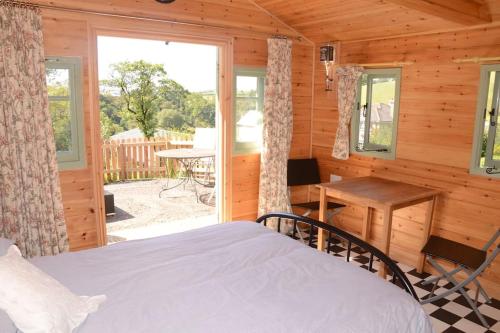 a bedroom in a log cabin with a bed and a desk at Woolcombe Cabin in East Allington