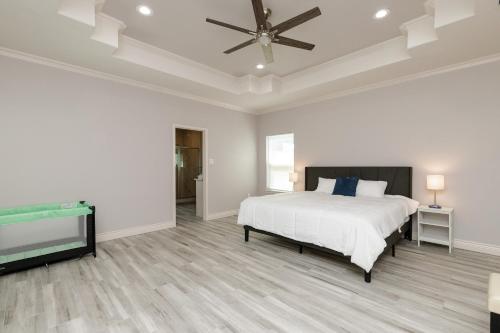 a white bedroom with a bed and a ceiling fan at Luxurious 4-Bedroom Retreat Near the Beach: King Suite, High-Speed WiFi, Free Parking in Corpus Christi