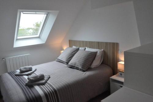 een slaapkamer met een bed met 2 handdoeken en een raam bij Villa An Castine avec spa pour 6pers proche plages in Saint-Cast-le-Guildo