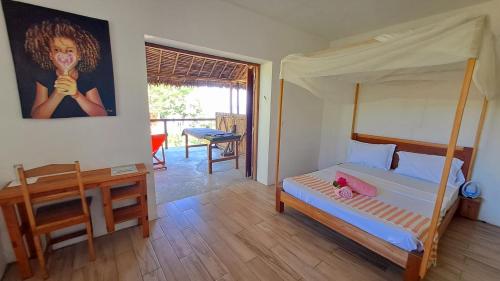 a bedroom with a bed with a canopy and a table at Villa c'est la vie in Nosy Komba