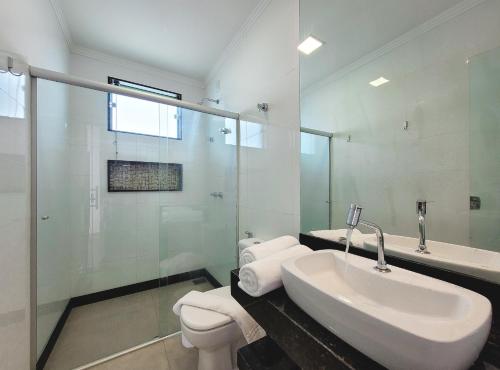 a white bathroom with a sink and a shower at Riviera Capitólio Hotel in Capitólio