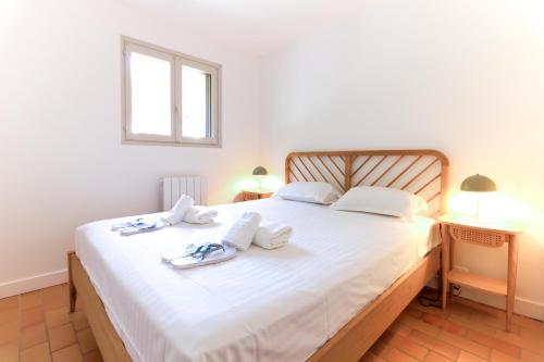 a bedroom with a large white bed with towels on it at SELECT'soHOME - Superbe Duplex dans le quartier Saint-Clair au Lavandou - PARCFO16 in Le Lavandou