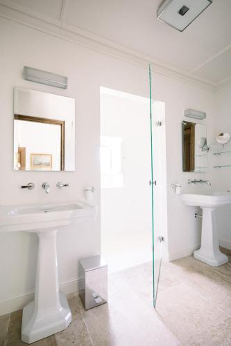 Un baño con dos lavabos y una ducha de cristal. en Le Domaine du Fortin, en Ménerbes