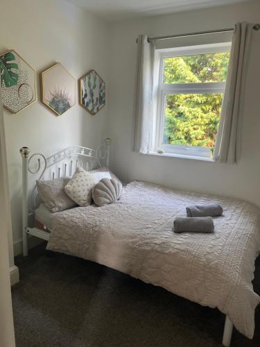 1 dormitorio con cama con almohadas y ventana en Stunning Bebington Maisonette - large private drive and entrance, good transport links en Bebington