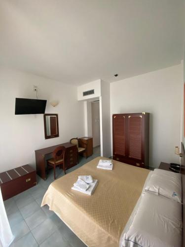 a hotel room with two beds and a desk at Hotel America in Marina di Camerota