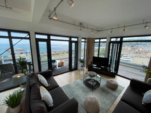 uma sala de estar com um sofá e uma televisão em Riviera Apartments - Five Stylish Penthouse Apartments with Unrivalled Sea Views of Teignmouth, Shaldon, The Jurassic Coastline & The Teign Estuary em Teignmouth