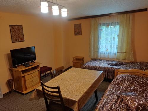 a hotel room with two beds and a table with a television at Holiday Home Lyubovo in Gabrovo