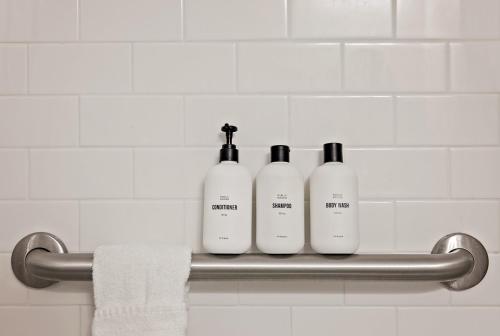 three shampoo bottles sitting on a towel rack in a bathroom at Placemakr Premier SoBro in Nashville