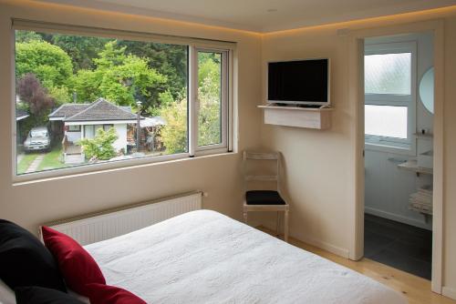 a bedroom with a bed and a window with a tv at Del Pescador Hotel Cabañas in Frutillar