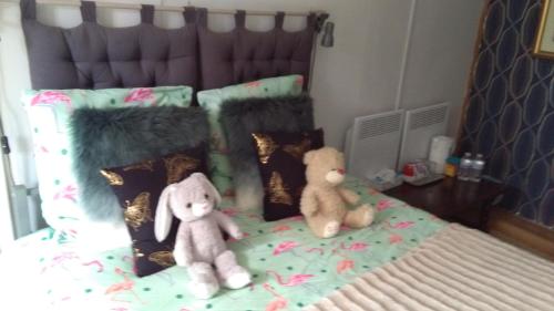 two stuffed animals sitting on top of a bed at white house in Saint-Germier