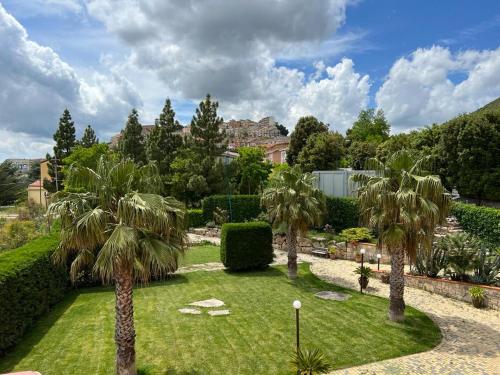 einen Garten mit Palmen und ein Gebäude im Hintergrund in der Unterkunft B&B PRIXIS in Prizzi