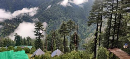 a view of a mountain with trees and buildings at Deep In Woods in Jibhi