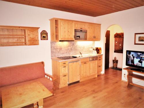 een keuken met houten kasten en een televisie en een bank bij Ferienhaus Waldwinkl in Grainau