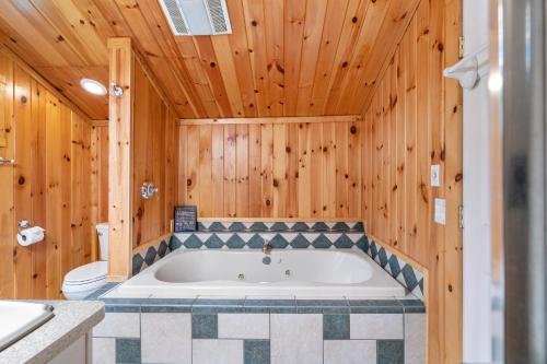 a bathroom with a tub in a wooden wall at Hide-A-Way Waterfront Cottages in Lake Luzerne