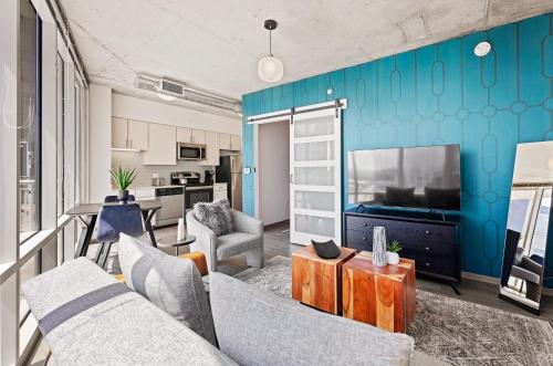 a living room with a couch and a tv at Placemakr Premier SoBro in Nashville