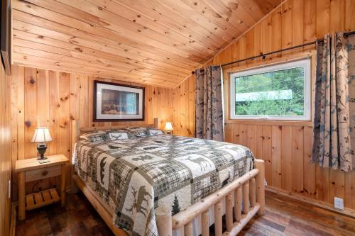 1 dormitorio con 1 cama en una cabaña de madera en Hide-A-Way Waterfront Cottages, en Lake Luzerne