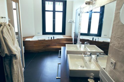 a bathroom with two sinks and two windows and a tub at Logis Les Loges du Parc in La Roche-Posay