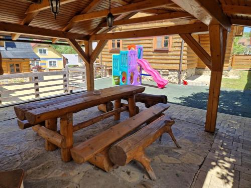 a wooden picnic table and a playground with a slide at Drevenice Osádka in Osádka