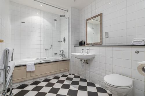 a bathroom with a toilet and a sink and a tub at Mercure Salisbury White Hart Hotel & Apartments in Salisbury