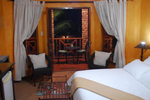 a bedroom with a bed and chairs and a balcony at 20 on Visarend in Malelane