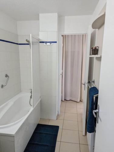 une salle de bain blanche avec une baignoire et une douche dans l'établissement T3 clim piscine chauffée proche de la plage parking dans village vacances, au Cap d'Agde