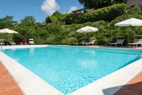 una piscina con sillas y sombrillas en Universal Harmony - Usignolo, en Dicomano