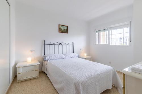 a white bedroom with a bed and two night stands at Coblanca 7 in Benidorm