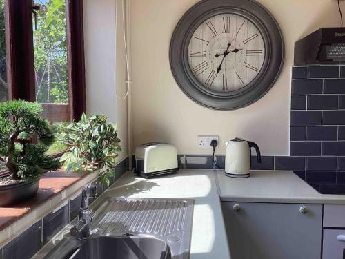 uma cozinha com um lavatório e um relógio na parede em The Annex at The Croft em Kingsley