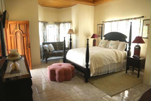 - une chambre avec un grand lit et une chaise dans l'établissement Jannetta's @Whimhill Bed & Breakfast, à Negril