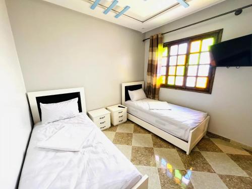 two beds in a room with a window at Unique Villa Castle With Pool in Essaouira
