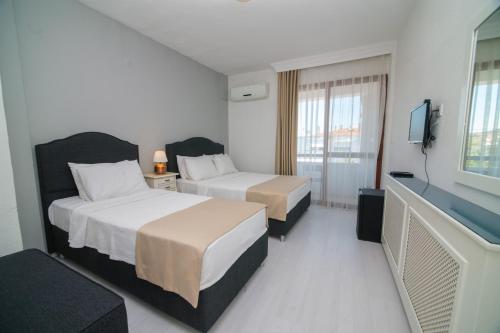 a hotel room with two beds and a flat screen tv at Cesurlar Hotel in Çeşme