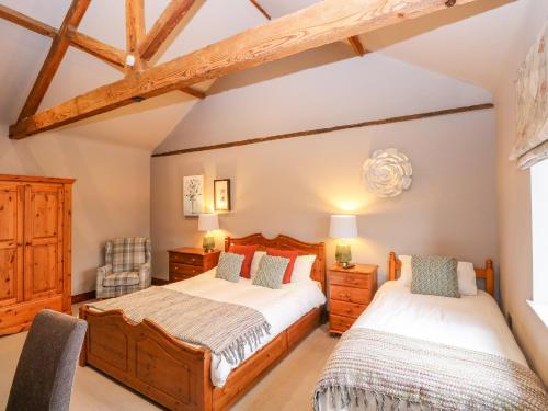 2 łóżka w sypialni z drewnianymi belkami stropowymi w obiekcie Barn Conversion w mieście Norwich