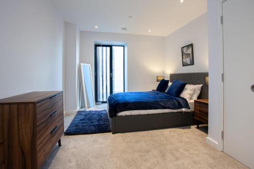 a bedroom with a bed and a dresser with a blue bedspread at Gorgeous 2 Bedroom Apartment in Manchester in Manchester