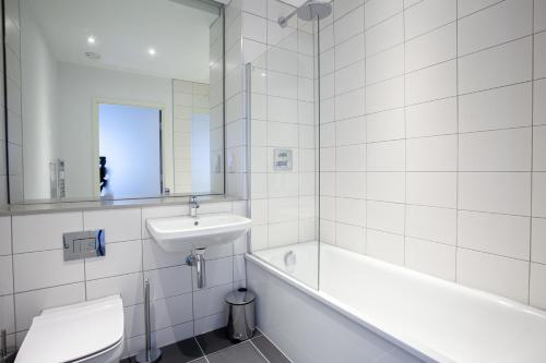 a white bathroom with a sink and a tub and a toilet at Gorgeous 2 Bedroom Apartment in Manchester in Manchester