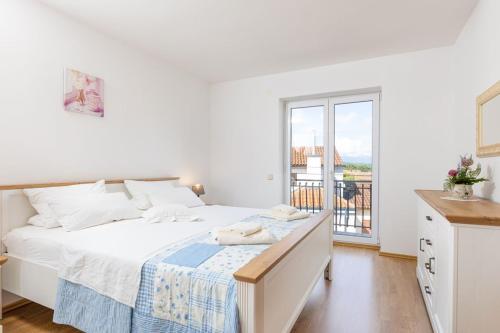 - une chambre blanche avec un grand lit et un balcon dans l'établissement Apartments Barjaktarić, à Malinska