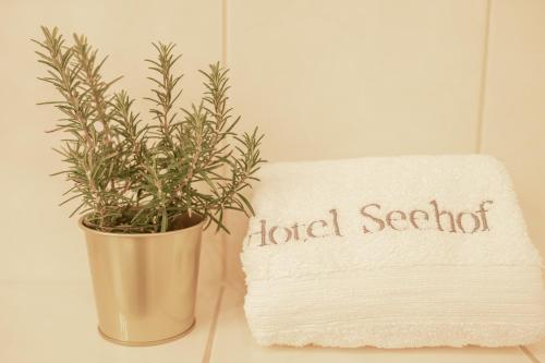 a plant in a pot next to a towel and a luck society sign at Hotel Seehof Norderney OHG in Norderney
