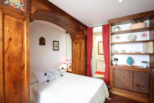 ein Schlafzimmer mit einem weißen Bett und einem hölzernen Torbogen in der Unterkunft Sikelia Apartment Taormina in Taormina