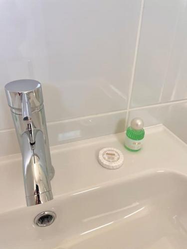 La salle de bains est pourvue d'un lavabo avec un robinet et une bougie verte. dans l'établissement Studio avec vue panoramique mer hippodrome, à Cagnes-sur-Mer