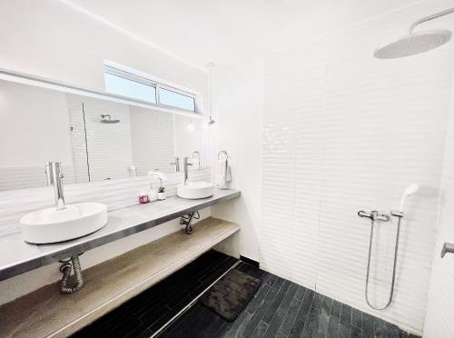 a white bathroom with two sinks and a shower at Comunidad Calle 13 Hotel Boutique in Santa Marta