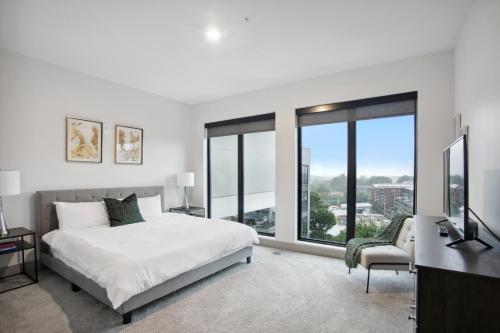 um quarto com uma cama, uma secretária e janelas em West Midtown Penthouse 2 bdrm em Atlanta