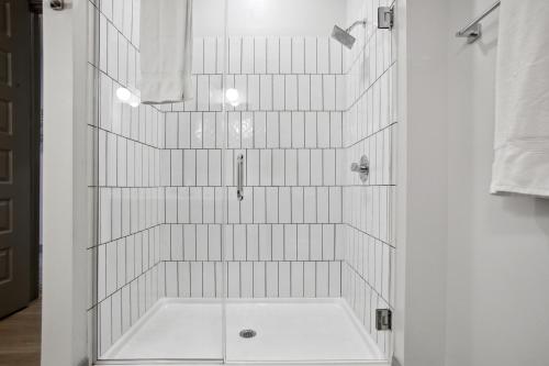 uma casa de banho com chuveiro e azulejos brancos em West Midtown Penthouse 2 bdrm em Atlanta