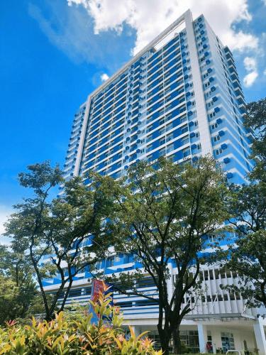 een hoog gebouw met bomen ervoor bij 11F Condo in Limketkai Center CDO in Cagayan de Oro