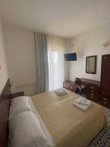 a hotel room with a bed with two towels on it at Hotel America in Marina di Camerota