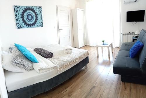 una camera da letto con un letto con cuscini blu e un divano di Ludna 3 a Niechorze