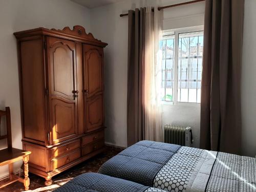 a bedroom with a wooden cabinet and a bed and a window at La Caseja Rural in Ossa de Montiel
