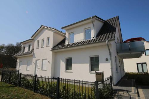 a white house with a fence in front of it at Haus Möwe - Whg 5 in Thiessow