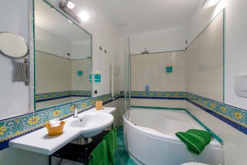 y baño con bañera, lavabo y espejo. en Amalfi Residence, en Conca dei Marini