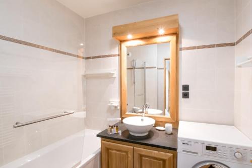 een badkamer met een wastafel, een spiegel en een bad bij Résidence Le Paradis in Chamonix-Mont-Blanc