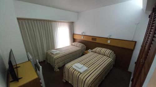 a hotel room with two beds and a window at Costanera Hotel in Puerto Madryn